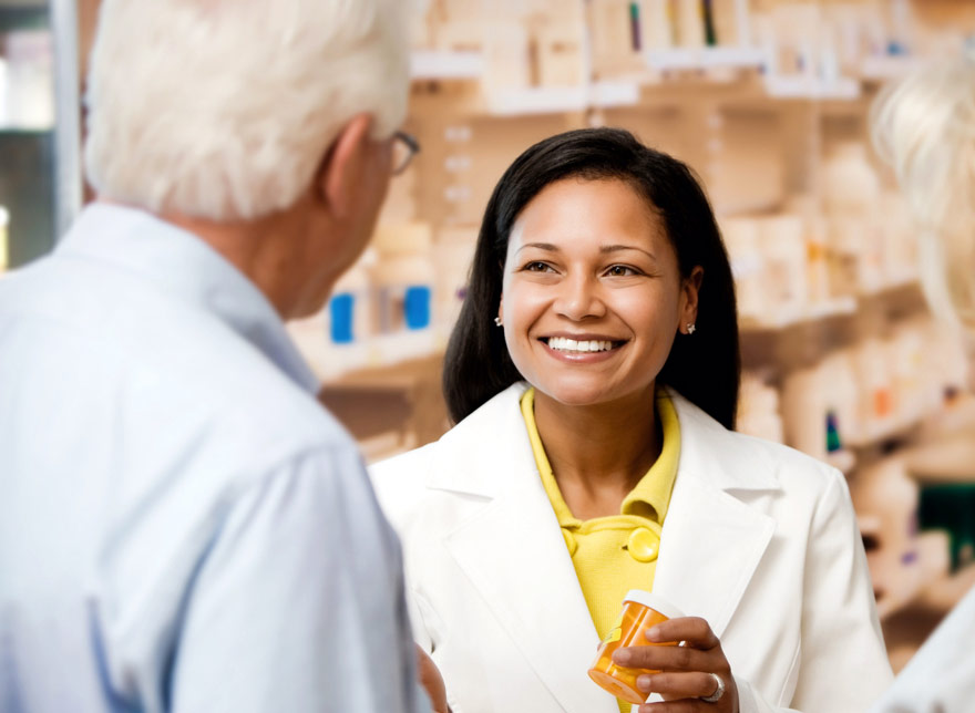 A pharmacist handing medicine to a man.